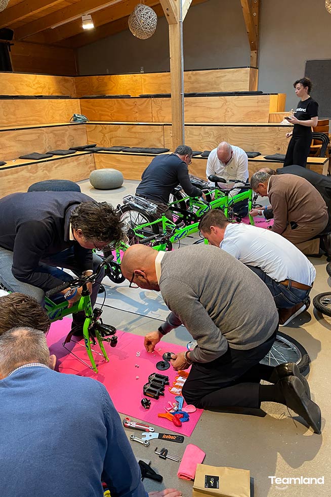 A group of people doing a Teamland Charity Bike Building competition in a bright room