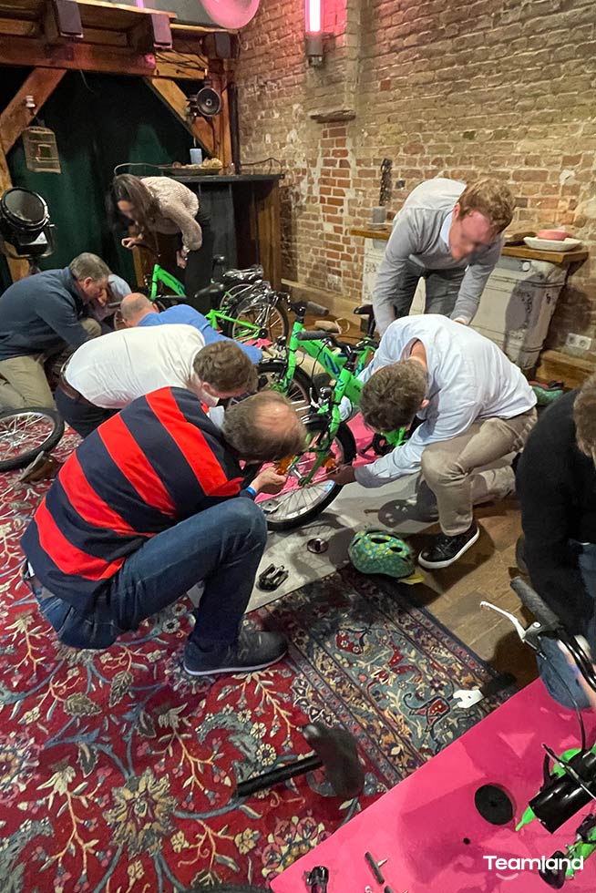 A group of people doing a Teamland Charity Bike Building competition in a hotel