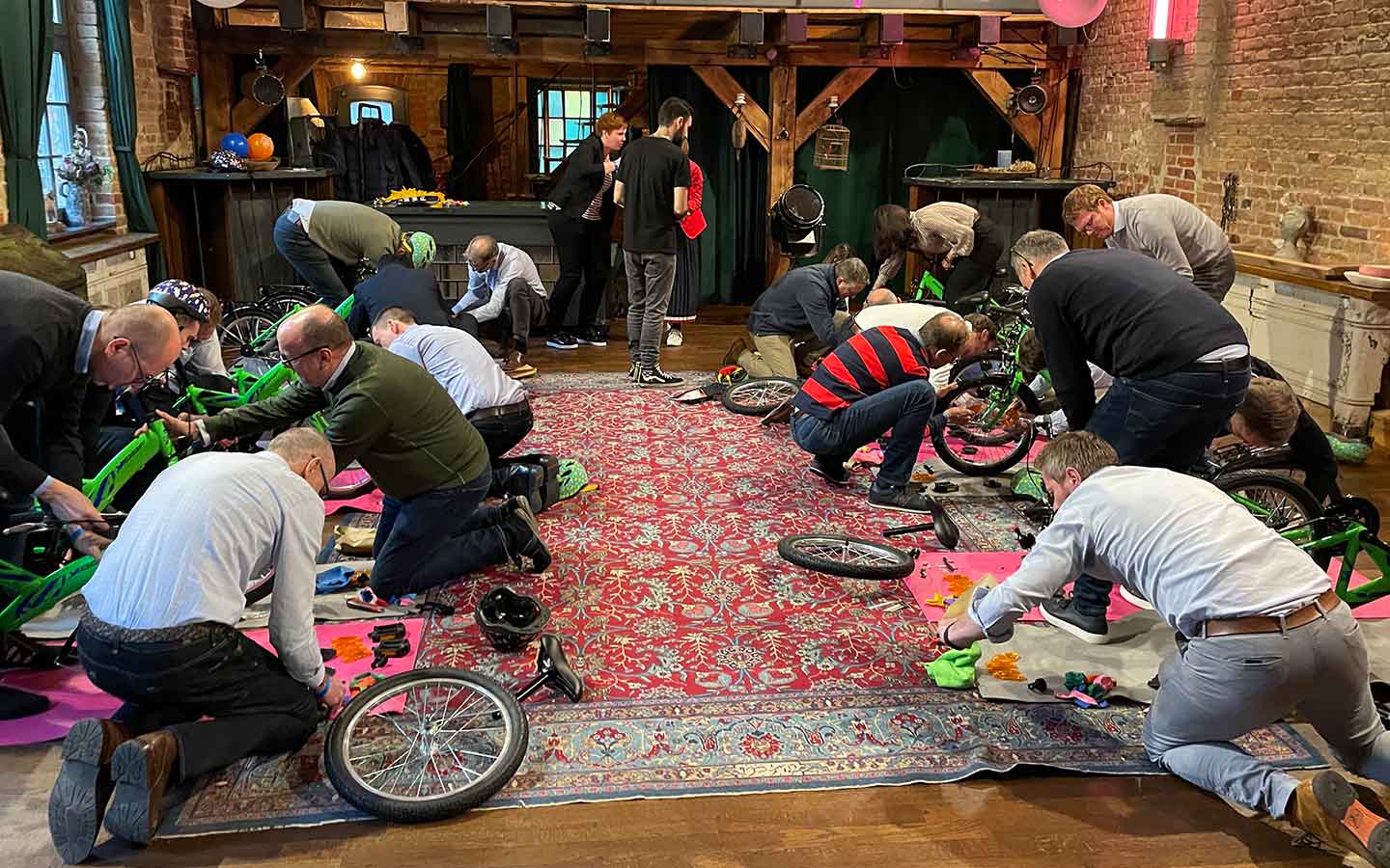 A group of people participating in a Teamland Charity Bike Build team building activity indoors in Europe