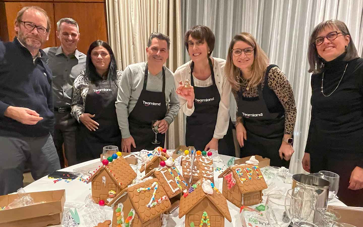 A group of people participating in a Teamland Holiday Gingerbread of Greatness team building activity indoors