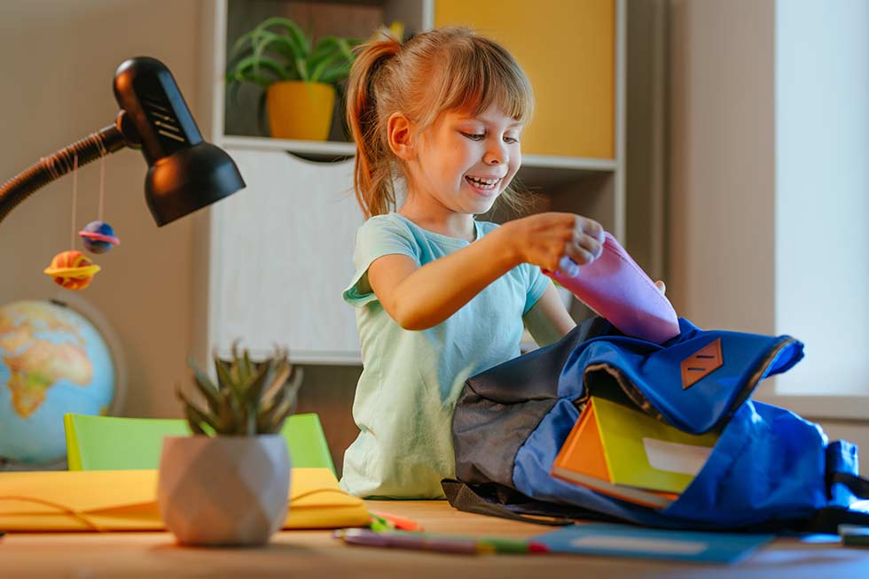 A elementary girl student opening school supplies gift