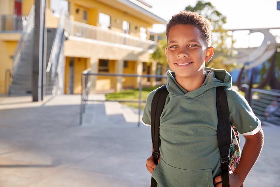 A child happy with Teamland team building Tools for School school supplies infront of school outdoors
